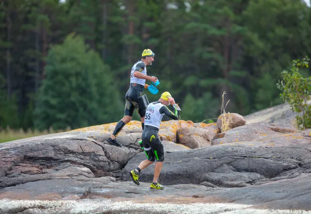 två simrun-deltagare springer på klipporna