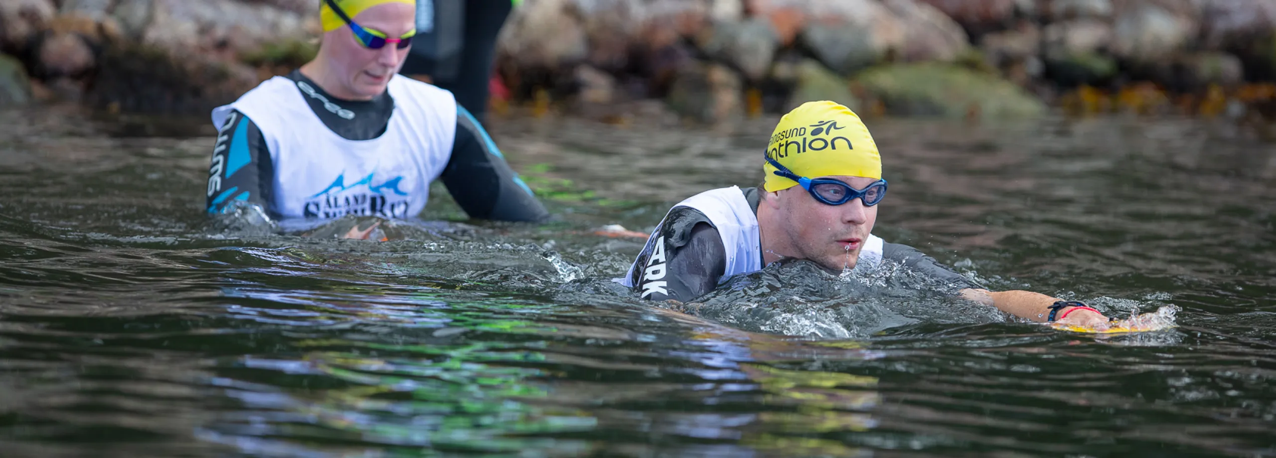 två swimrun-deltagare på väg ner i vattnet för simetapp
